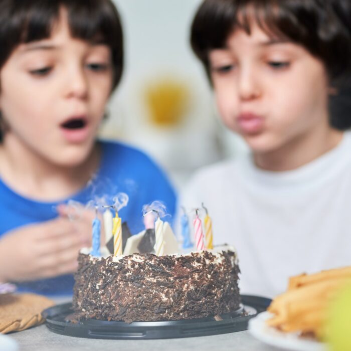 Birthday boys. Two little latin boys blowing candles on a birthday cake while celebrating birthday