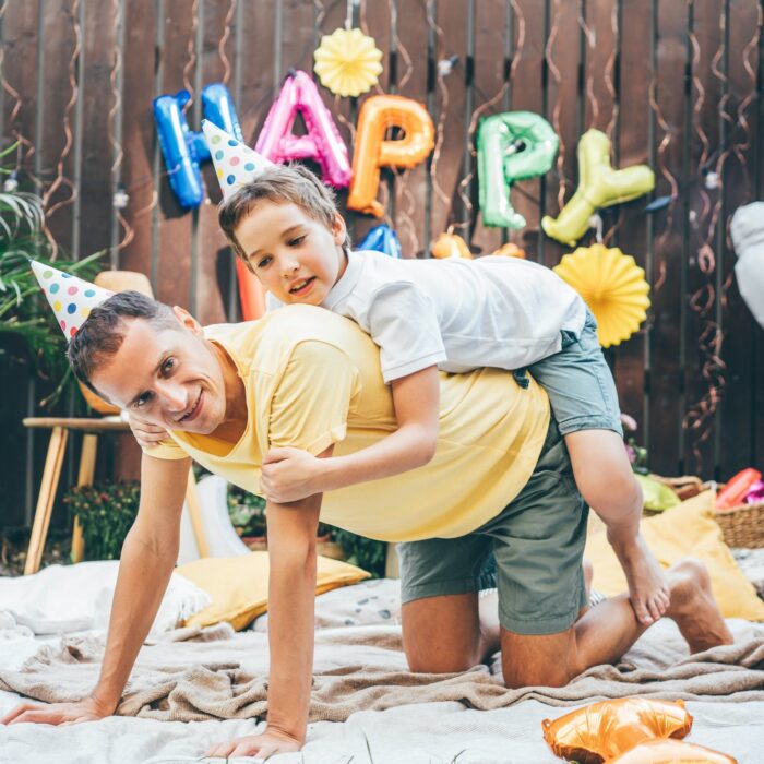 Father and son have fun and playing together at funny birthday celebration