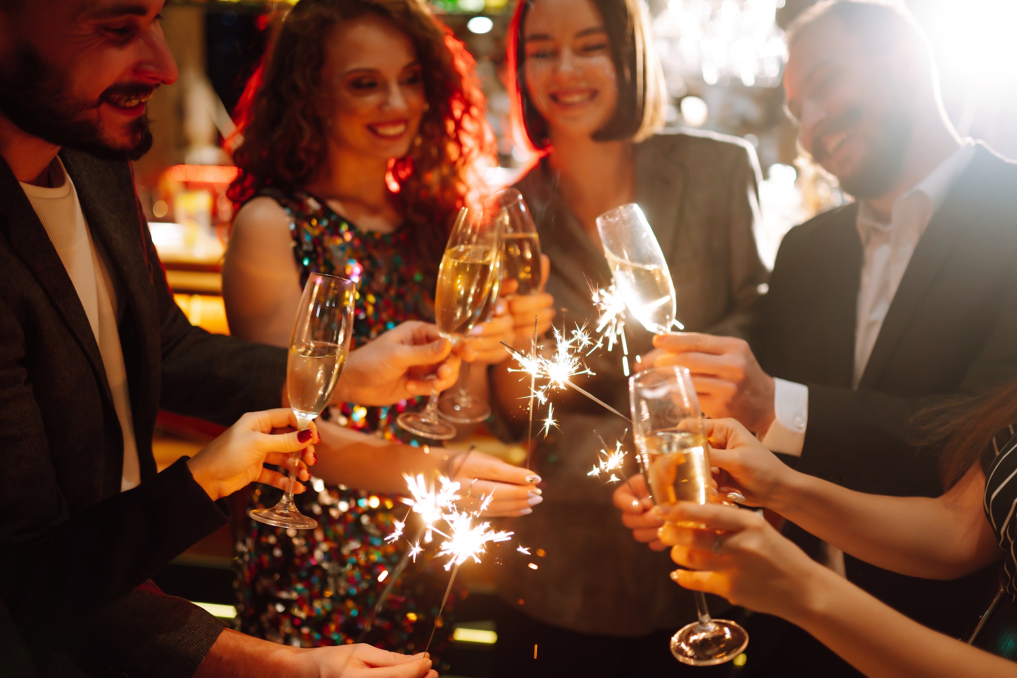 Glowing sparkles in hands. Group of happy people enjoying party with fireworks. Winter holiday.