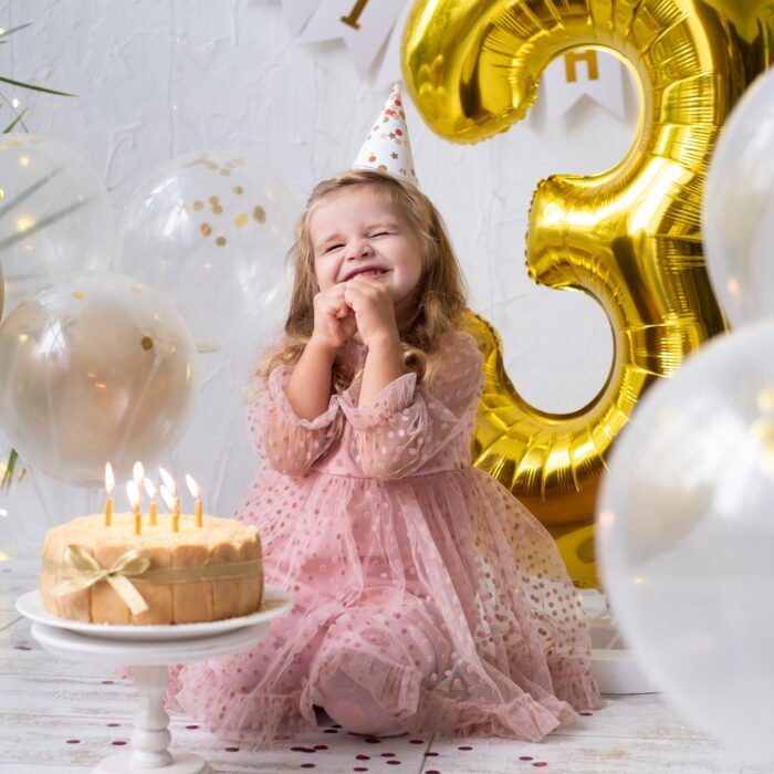 happy cute little child girl blowing candles on birthday cake and celebrating birthday